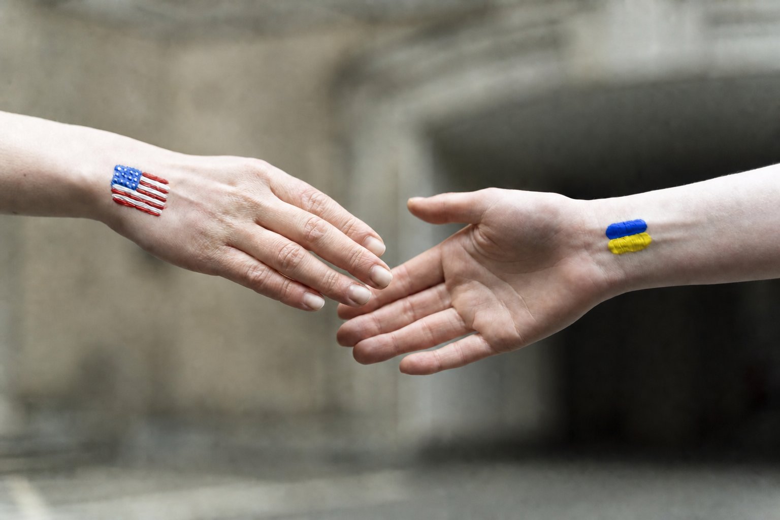 American and Ukrainian flags painted on two people's wrists, reaching to shake hands